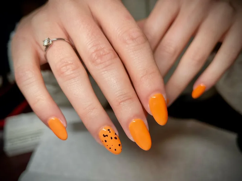 Bold orange nails with speckle accent